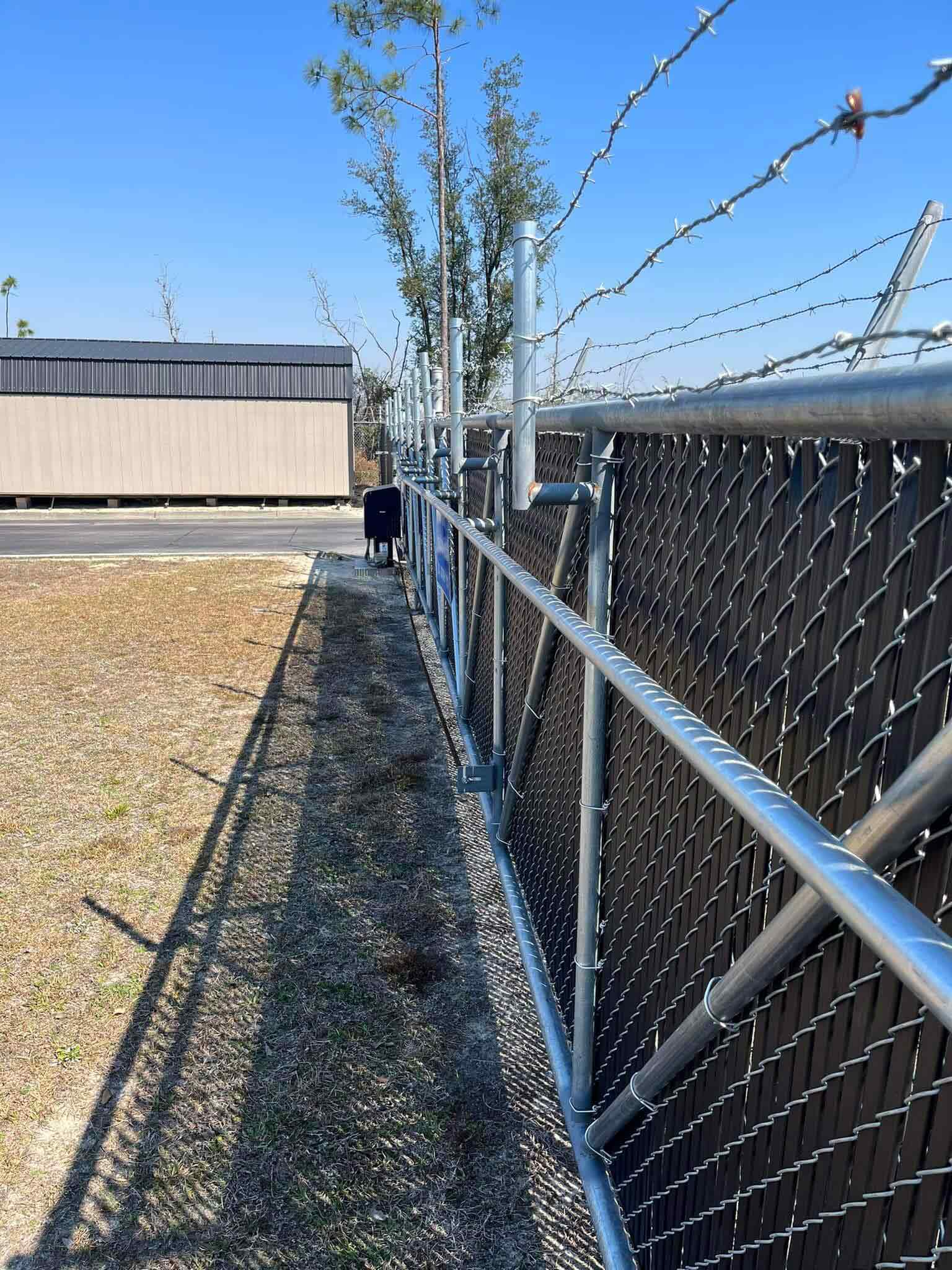 Photo of chain link fence with security barbed wire and gate operator