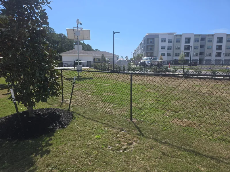 Black vinyl-coated chain link enclosure installed by Mr. Fence at a commercial property in Miramar Beach
