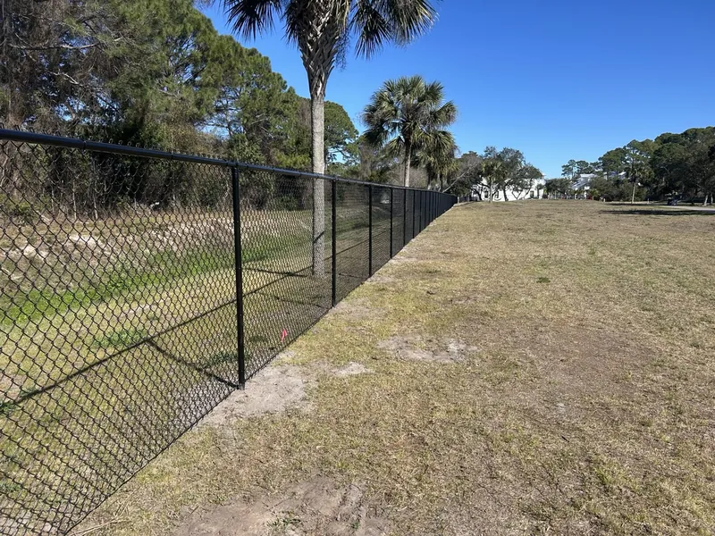 Black vinyl-coated chain link fence on public property in Miramar Beach
