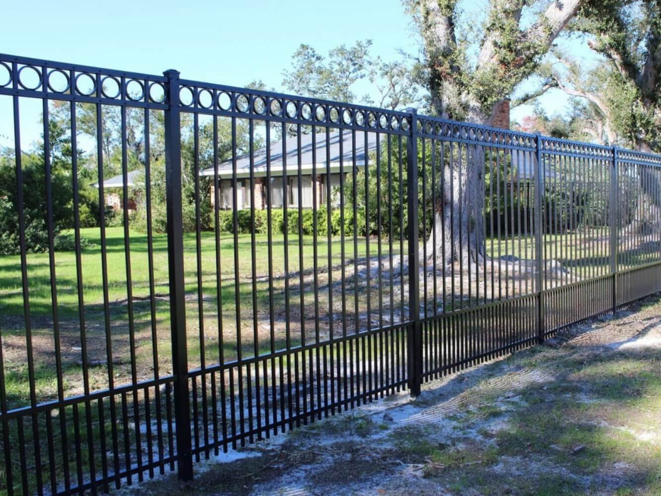 Black ornamental aluminum fence with decorative rings beside a lawn with large trees
