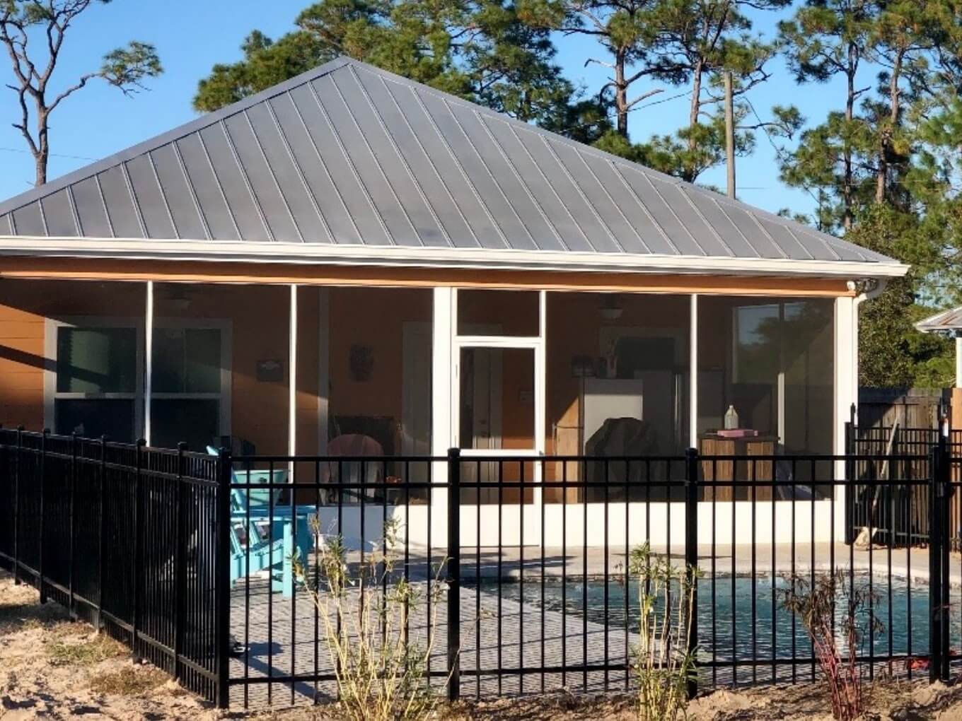 Black aluminum fence enclosing a pool area seen from inside a screened porch