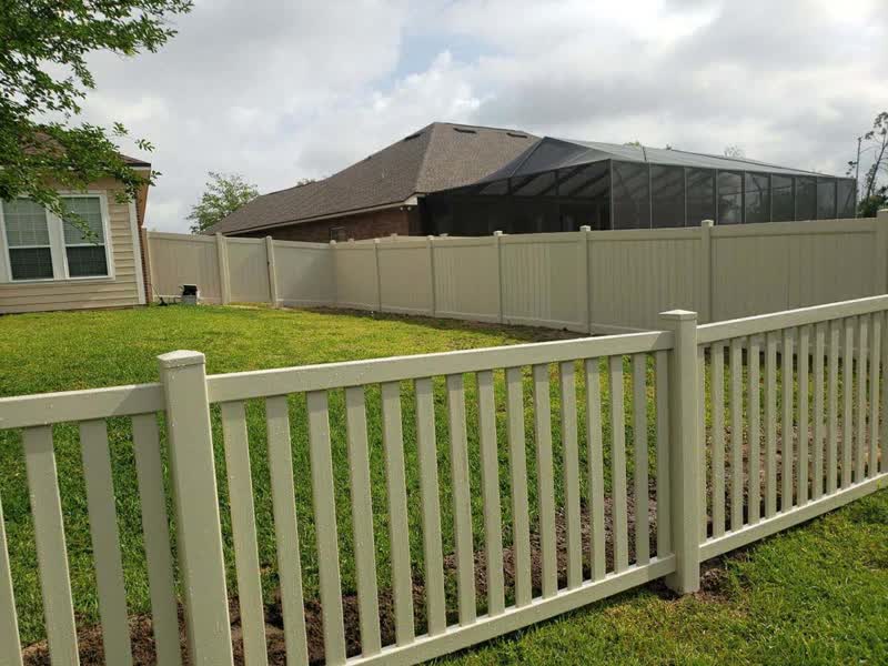 Solid tan vinyl privacy fence in a shaded backyard