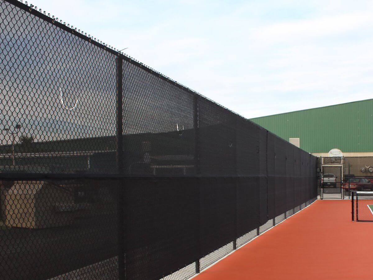 Black chain link fence with windscreen at a sports court