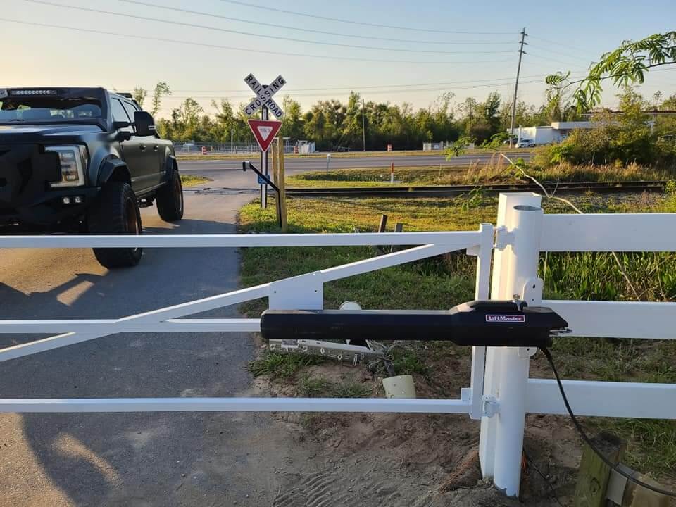 Automatic gate operator on a white ranch rail driveway gate