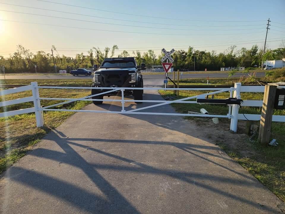 White vinyl ranch-style fence with a double-swing driveway gate installed in the Panama City area