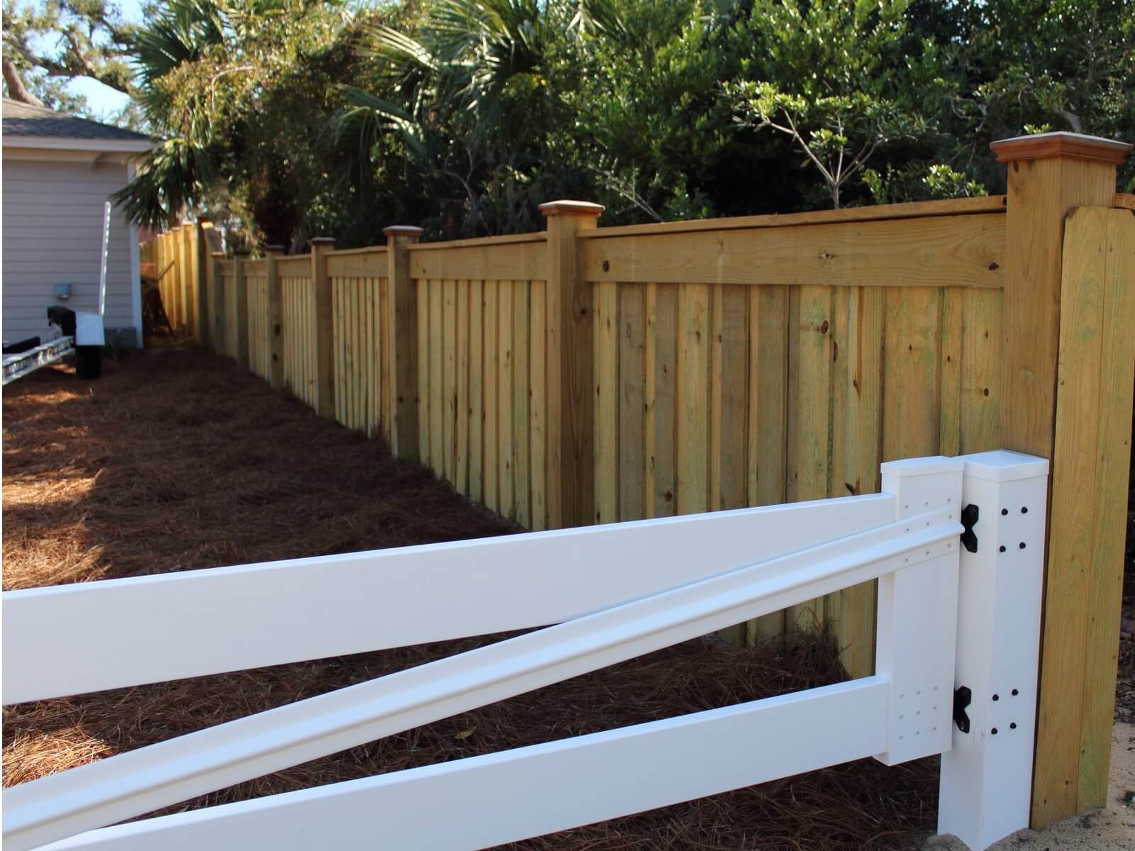 Wood privacy fence with a white ranch rail gate