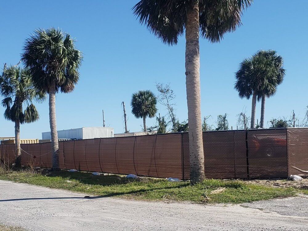 Temporary construction fence with brown windscreen along a job site