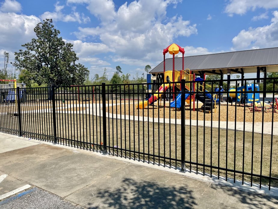 Black aluminum fence enclosing a playground