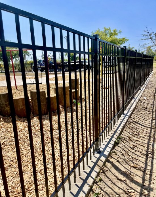 Black aluminum spear-top fence along a mulch bed