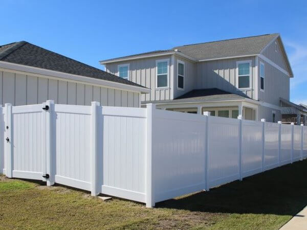 White vinyl privacy fence beside a two-story home