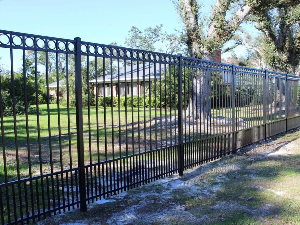 Black aluminum ornamental fence bordering a spacious yard with tall mossy oak trees