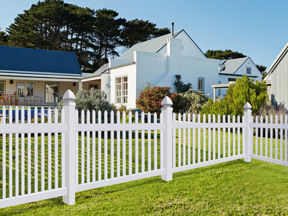 White vinyl picket fence lining the front yard of a two-story white home