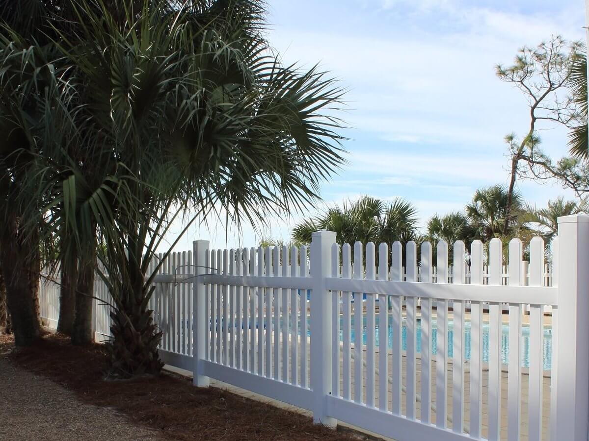 White vinyl picket fence in a landscaped yard