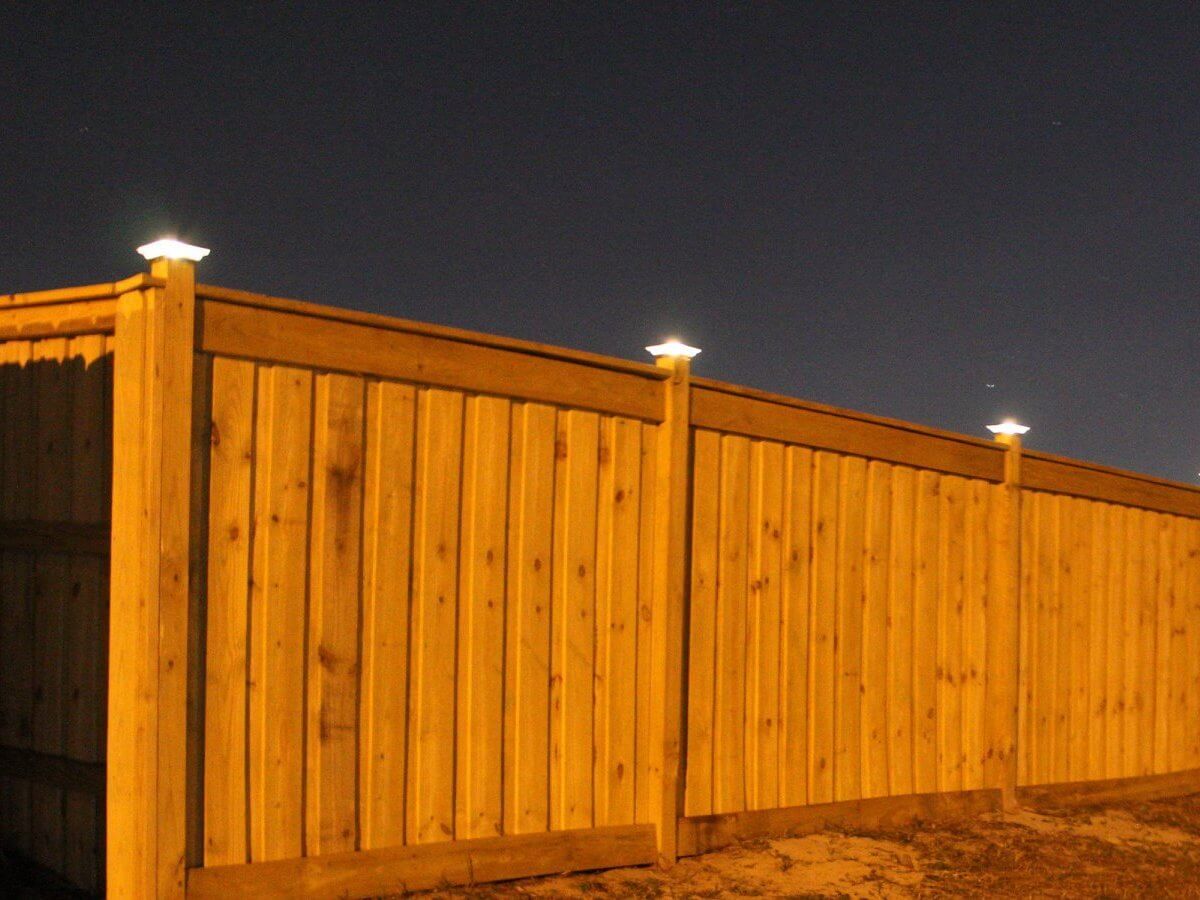 Wood privacy fence photographed at night with lit post caps, a Bay County installation